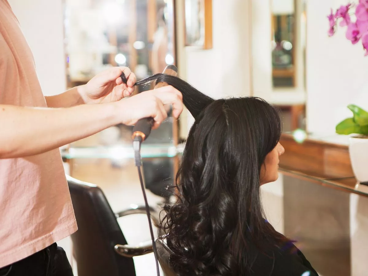0_Hairdresser-using-curling-tongs-on-customers-long-black-hair-in-salon